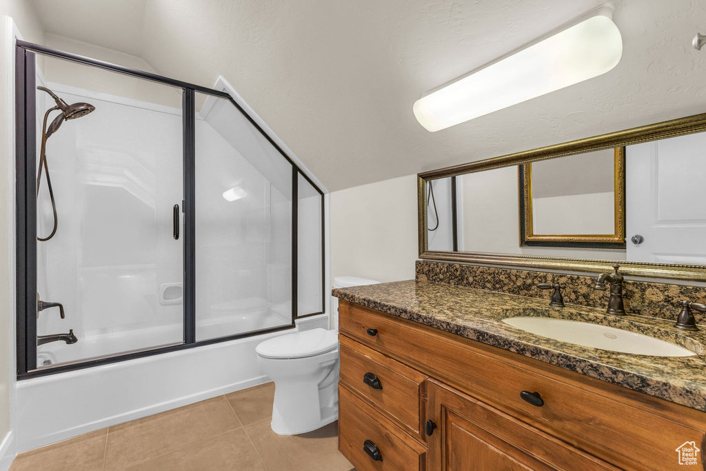 Bathroom with bath / shower combo with glass door, tile patterned flooring, vanity, and toilet