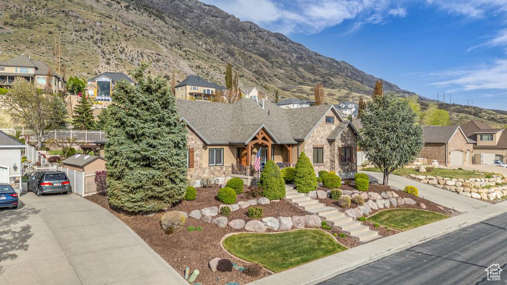 Tudor home with a residential view, a mountain view, stone siding, concrete driveway, and stairs