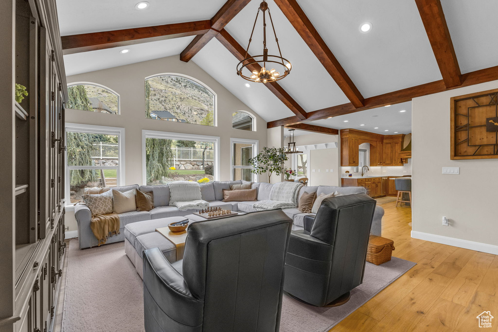 Living area featuring beam ceiling, high vaulted ceiling, and an inviting chandelier