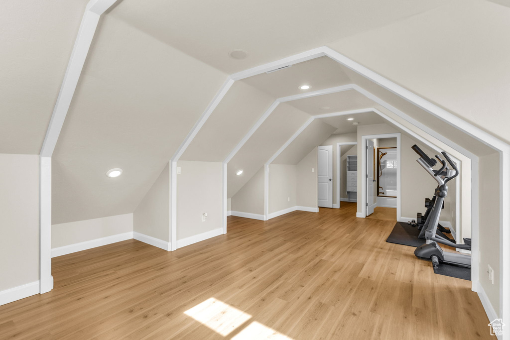 Additional living space featuring baseboards, vaulted ceiling, light wood-style floors, and recessed lighting