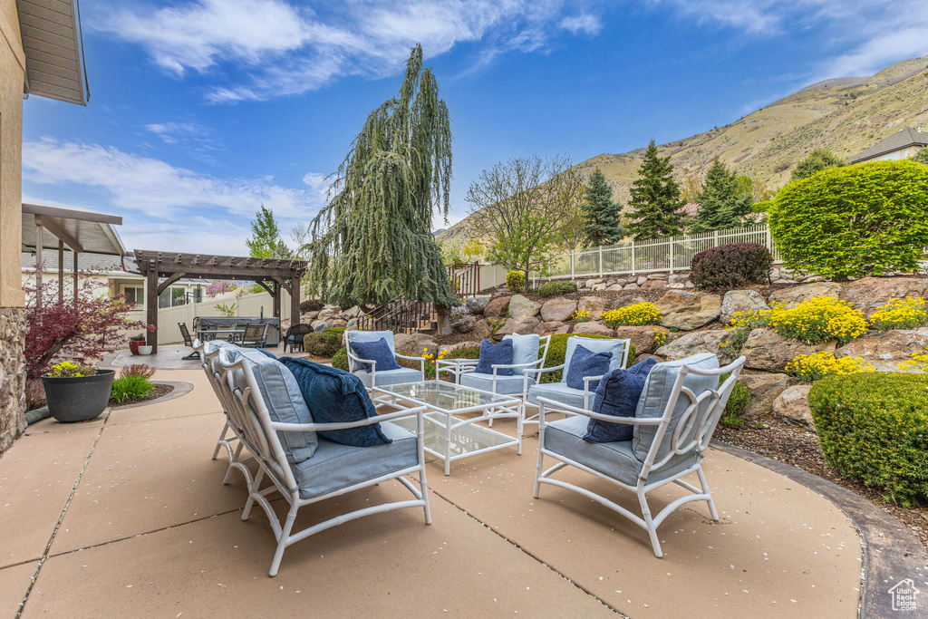 View of patio with a pergola, outdoor lounge area, fence, and a mountain view