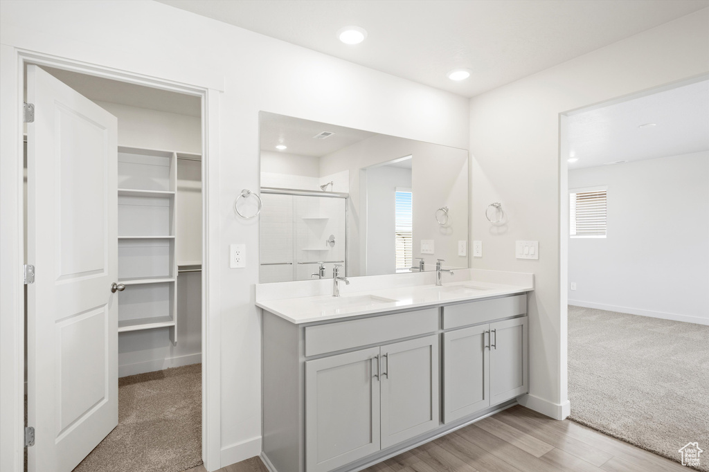 Full bath featuring a shower stall, double vanity, a spacious closet, recessed lighting, and wood finished floors