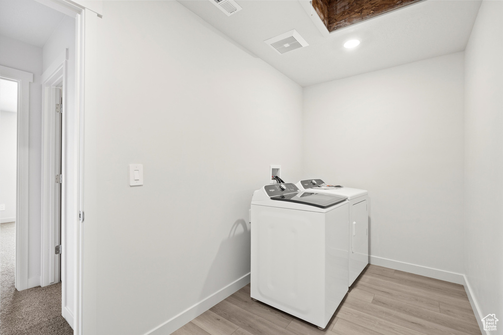 Laundry room featuring separate washer and dryer, light wood finished floors, and recessed lighting