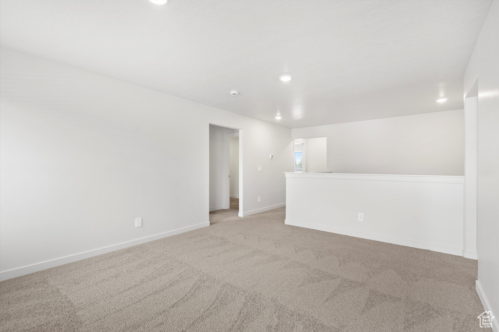 Empty room with light colored carpet and recessed lighting