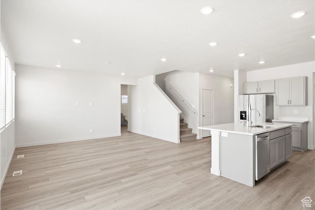 Kitchen with gray cabinets, stainless steel appliances, recessed lighting, light wood finished floors, and light countertops