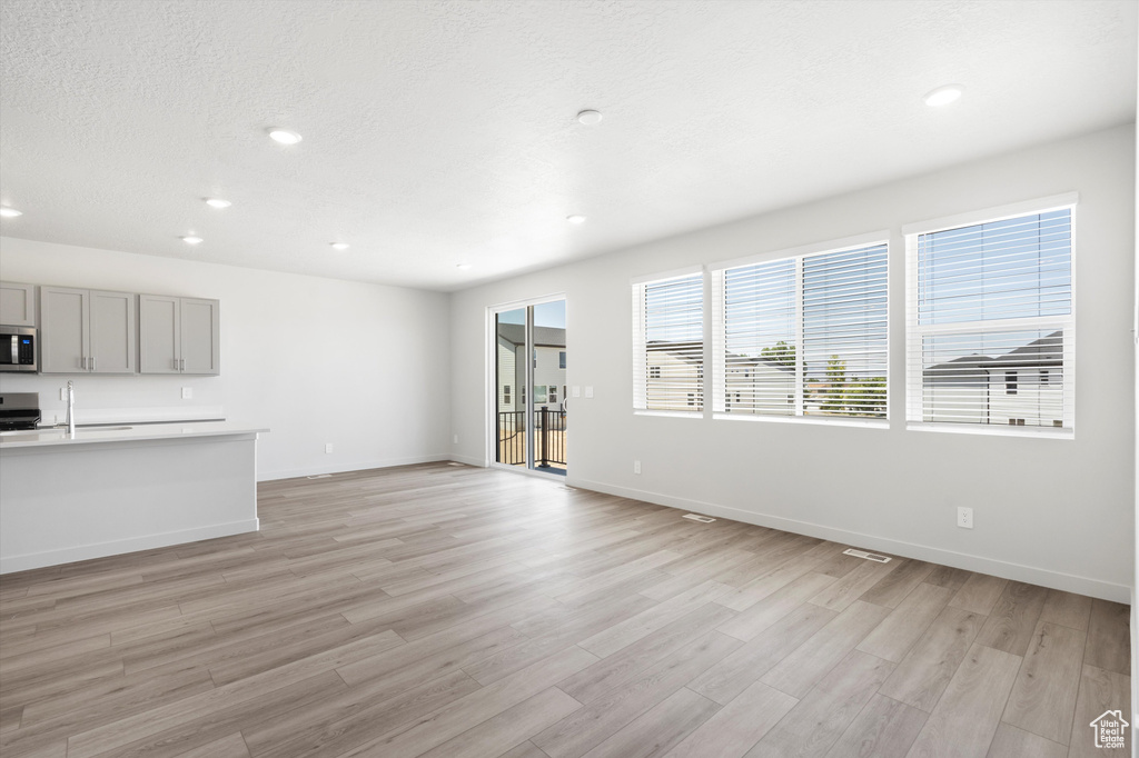 Unfurnished living room featuring recessed lighting, light wood-style flooring, and a textured ceiling