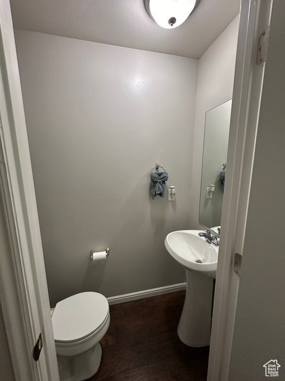 Bathroom featuring a sink, toilet, wood finished floors, and baseboards