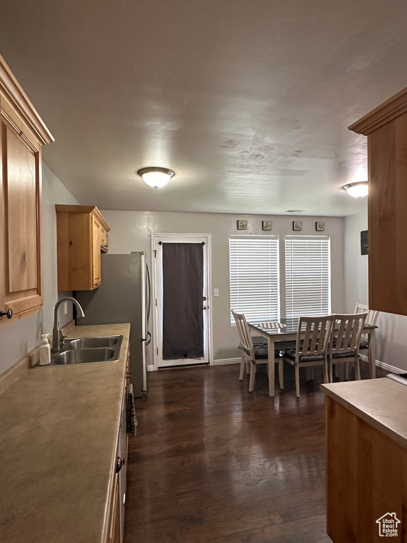 Kitchen with light brown cabinetry, light countertops, a sink, dark wood-type flooring, and baseboards