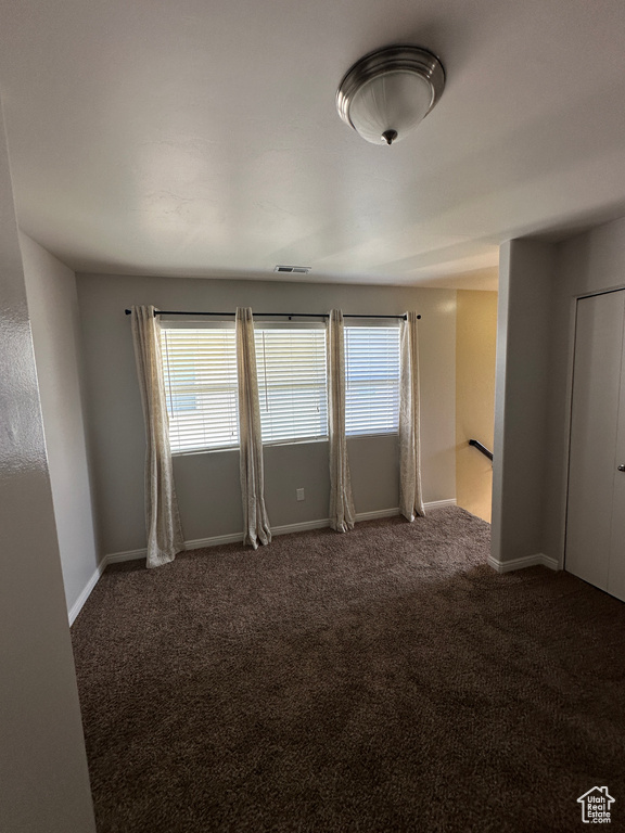 Unfurnished room featuring a wealth of natural light, carpet floors, visible vents, and baseboards