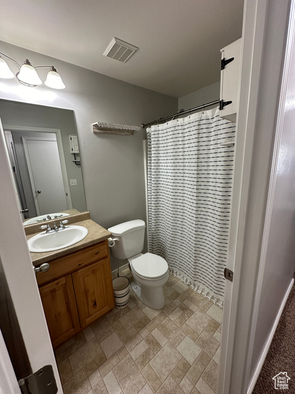Full bath featuring stone finish floor, visible vents, toilet, vanity, and a shower with curtain