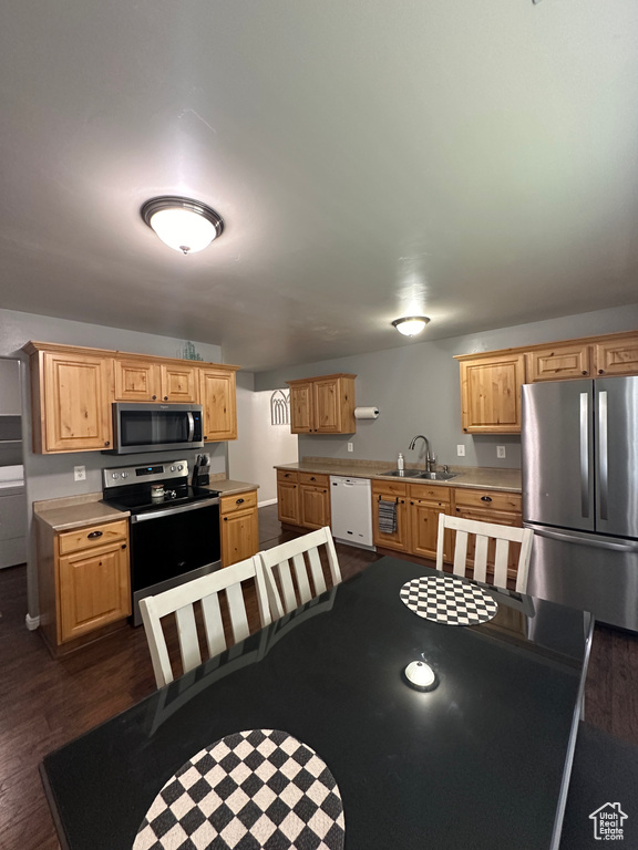 Kitchen featuring light countertops, light brown cabinets, a sink, appliances with stainless steel finishes, and dark wood-style flooring