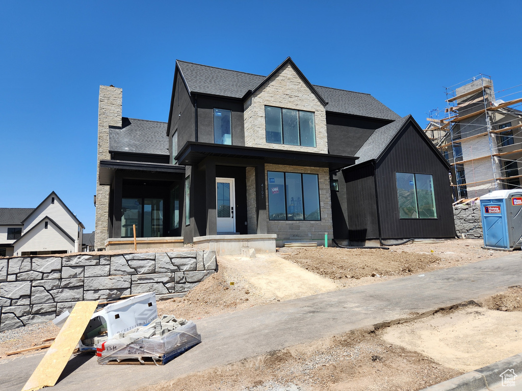 View of front of home with a chimney and roof with shingles