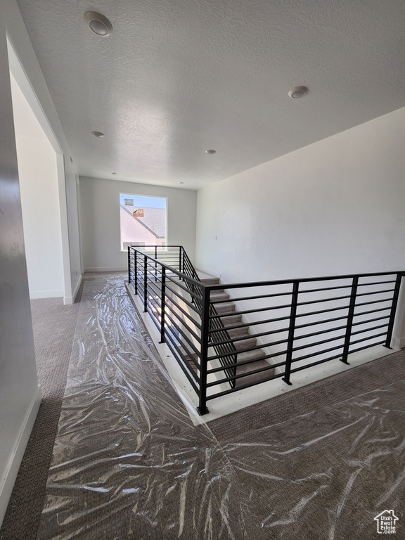 Stairs featuring a textured ceiling and baseboards