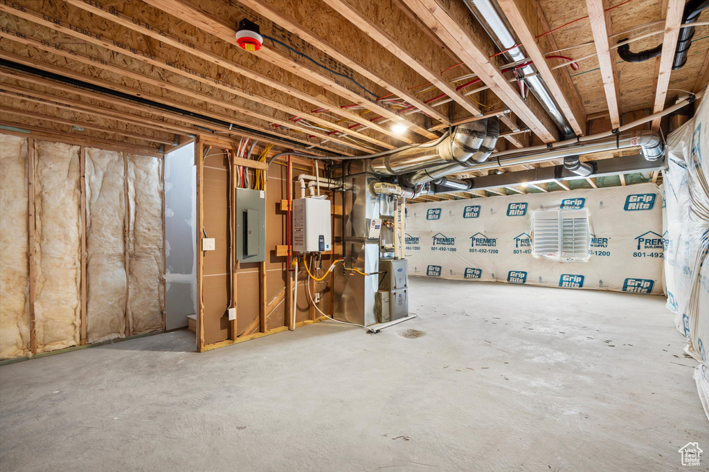 Unfinished below grade area featuring electric panel and heating unit