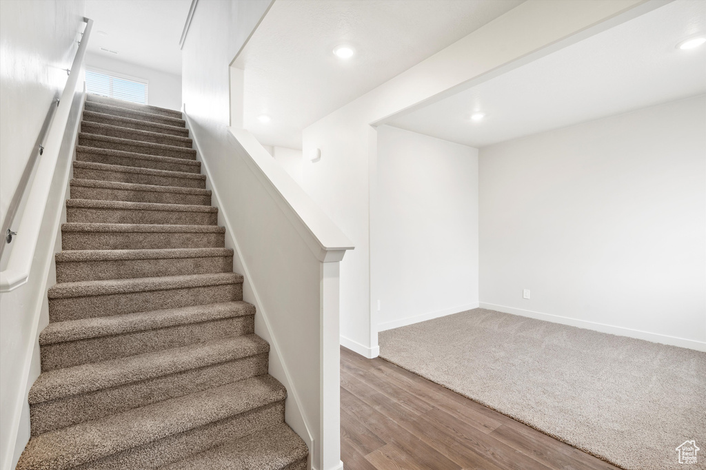 Stairway with wood finished floors and recessed lighting