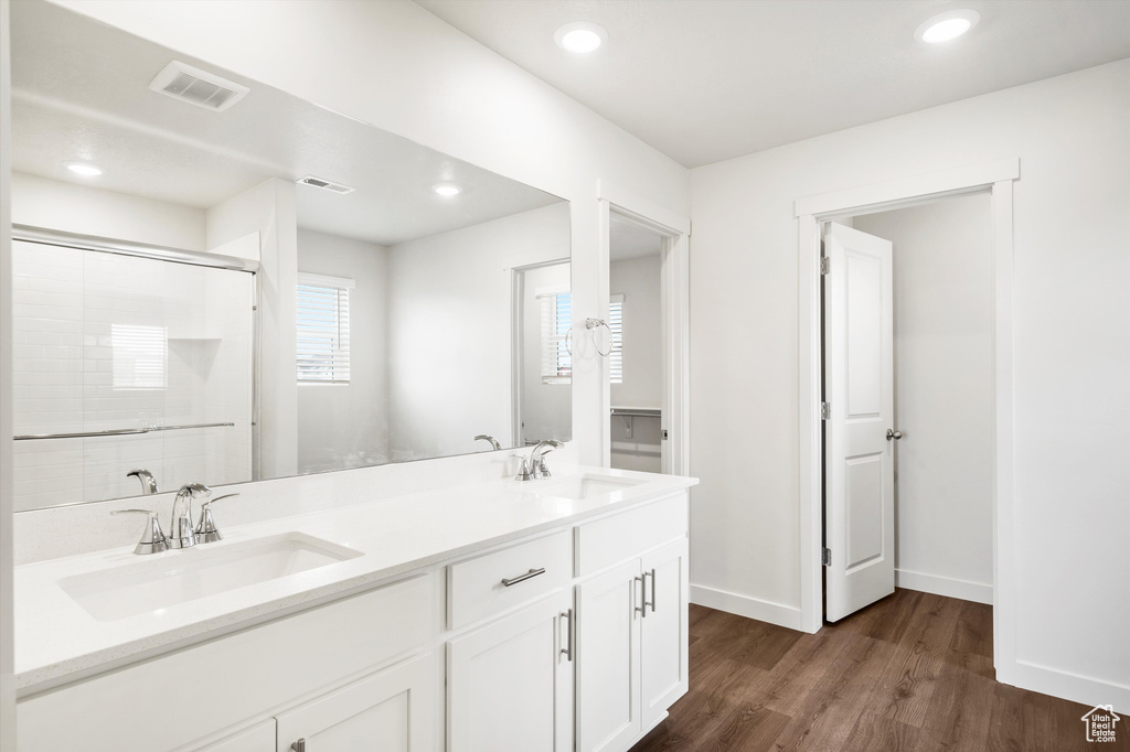 Bathroom featuring wood finished floors, double vanity, an enclosed shower, and recessed lighting