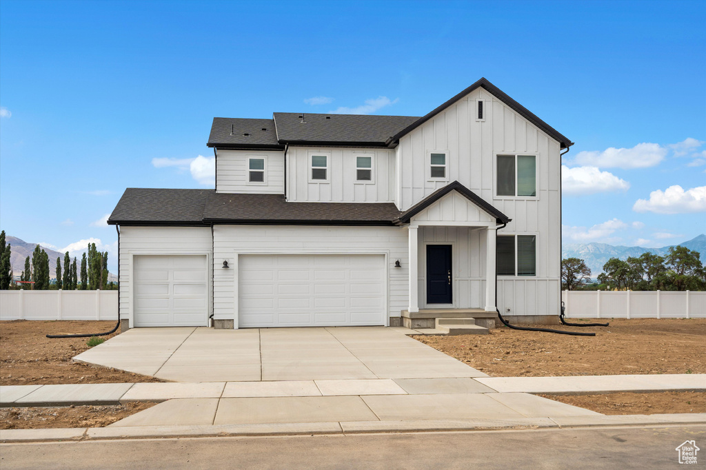 Modern inspired farmhouse with a mountain view, board and batten siding, driveway, a garage, and a shingled roof