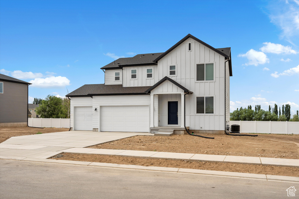 Modern farmhouse style home featuring board and batten siding, driveway, a garage, and roof with shingles