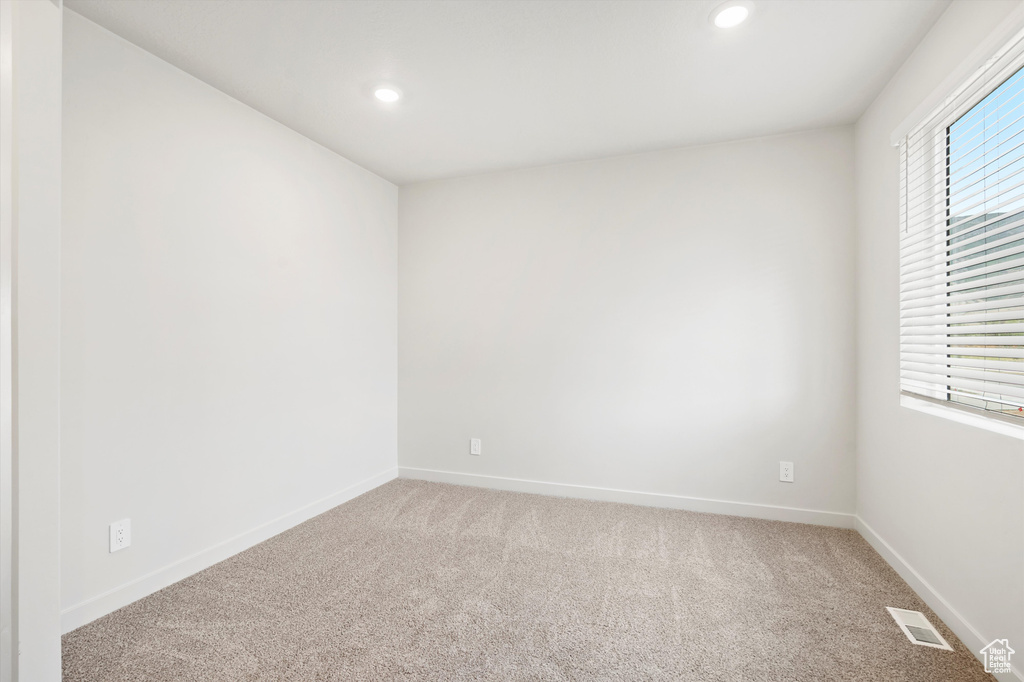 Unfurnished room featuring light colored carpet, healthy amount of natural light, and recessed lighting