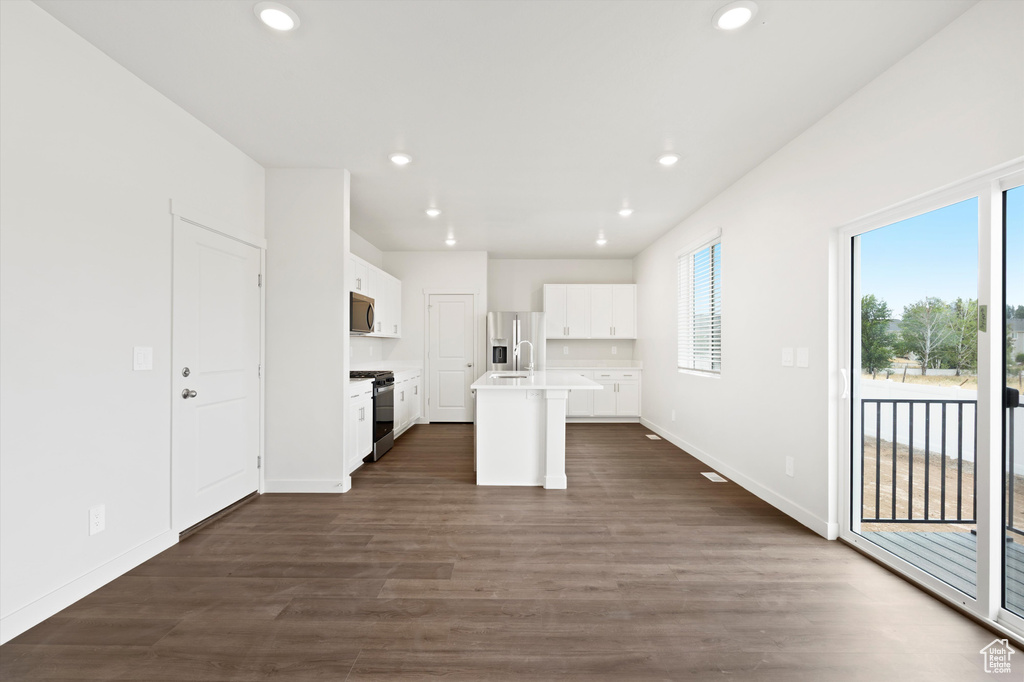 Kitchen featuring stainless steel appliances, recessed lighting, healthy amount of natural light, a kitchen island with sink, and light countertops