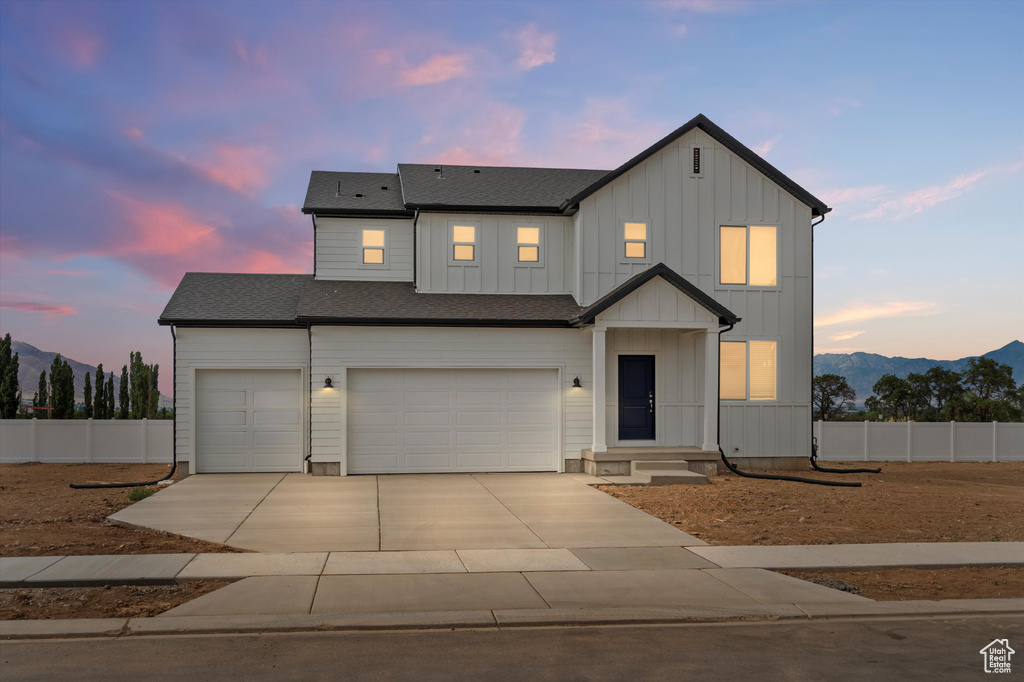 Modern farmhouse with a mountain view, concrete driveway, board and batten siding, and an attached garage