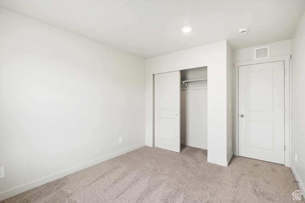 Unfurnished bedroom featuring light colored carpet, a closet, and recessed lighting