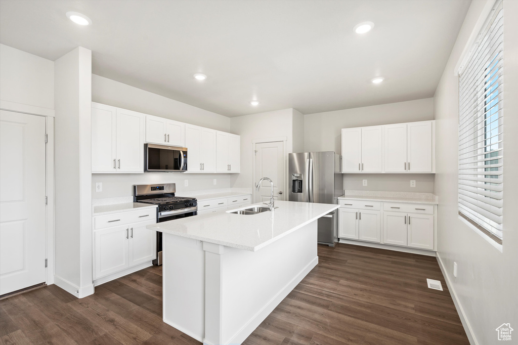 Kitchen featuring stainless steel appliances, dark wood-style floors, white cabinets, and recessed lighting