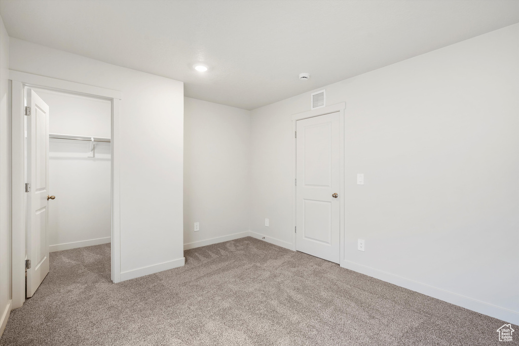 Unfurnished bedroom with carpet, a walk in closet, and recessed lighting