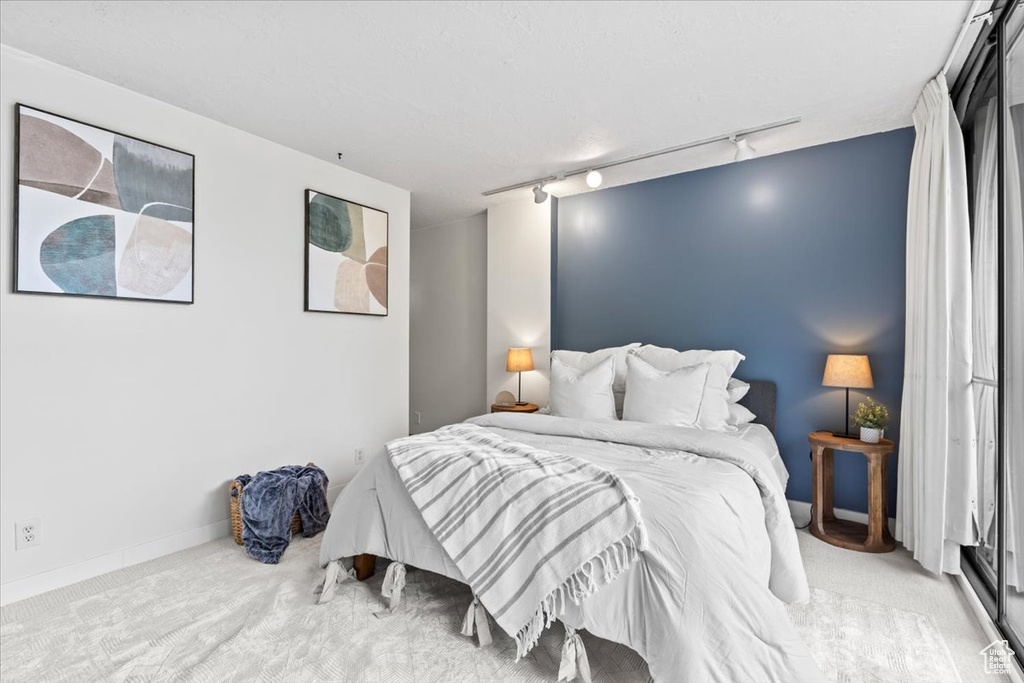 Bedroom featuring track lighting, carpet flooring, and baseboards