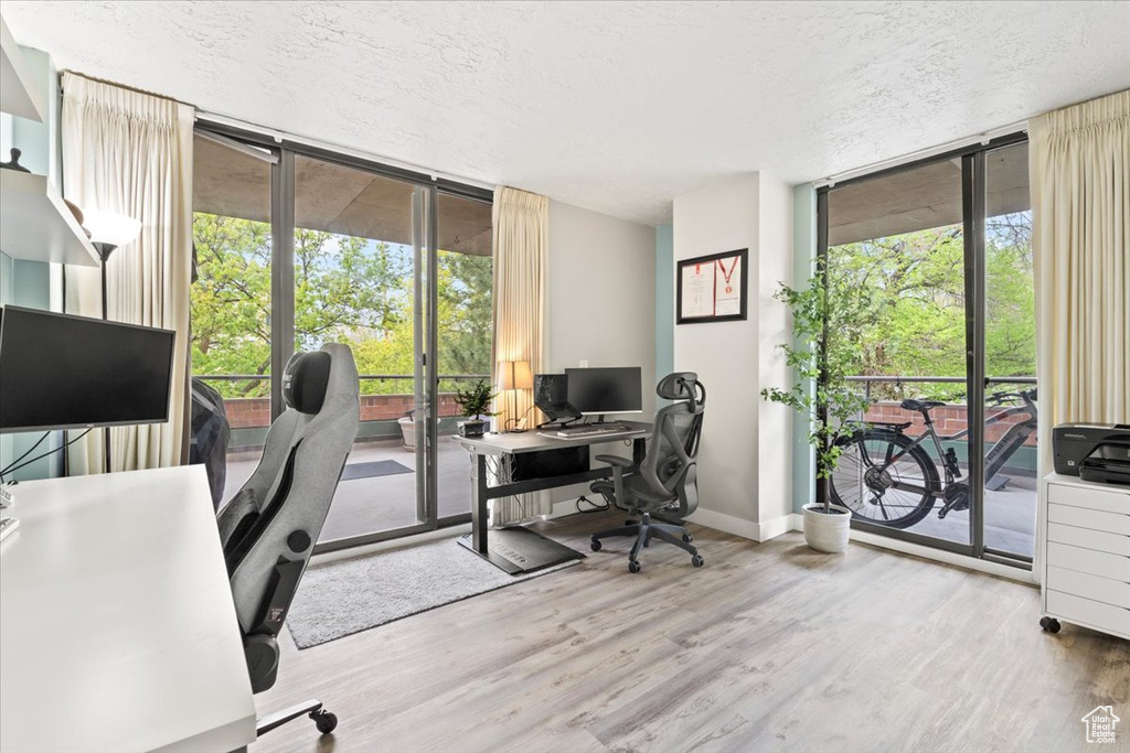 Office area with floor to ceiling windows, wood finished floors, and a wealth of natural light