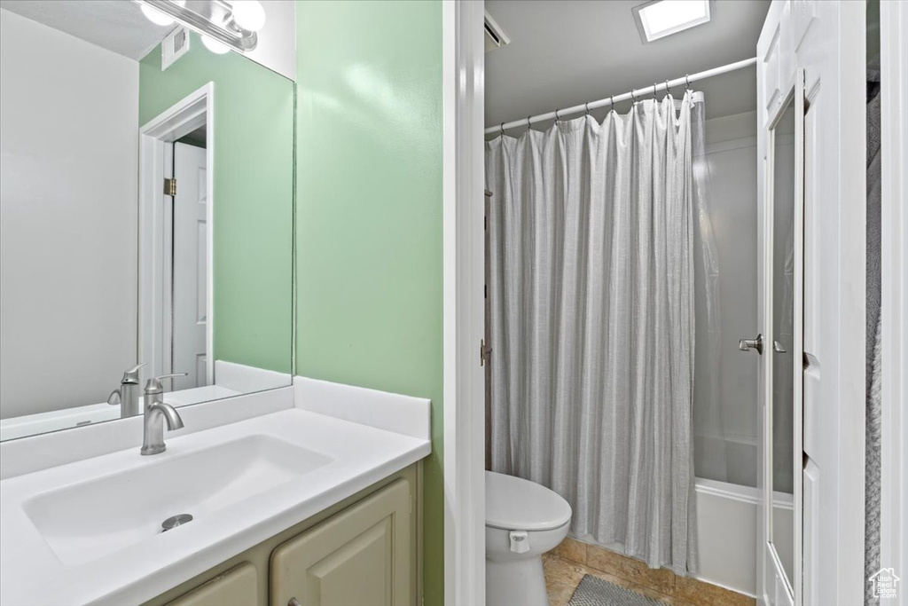 Bathroom featuring tile patterned floors, vanity, shower / bathtub combination with curtain, toilet, and visible vents