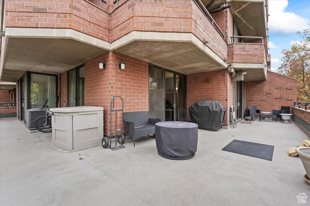 View of patio with central AC unit, a grill, and a balcony