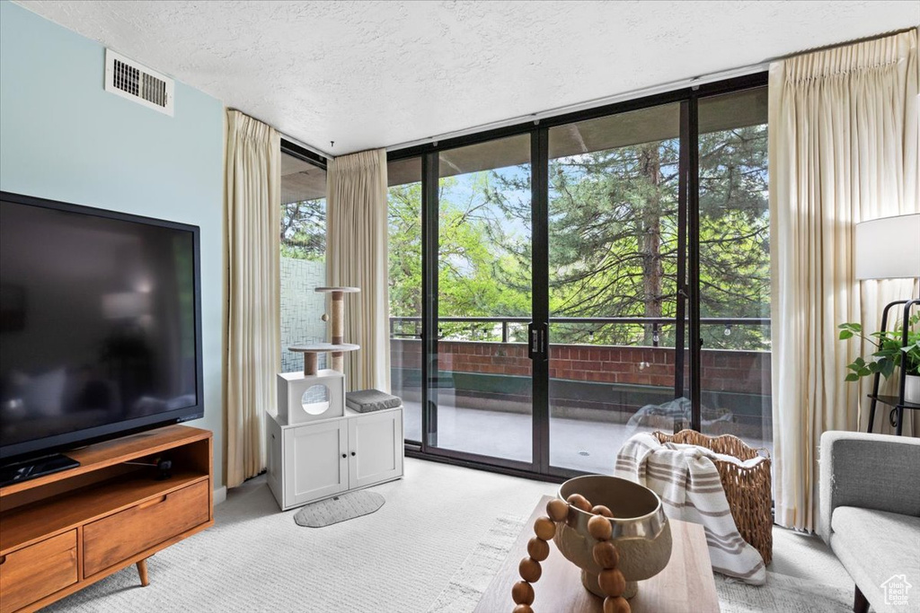 Living room featuring light carpet, visible vents, a textured ceiling, and floor to ceiling windows