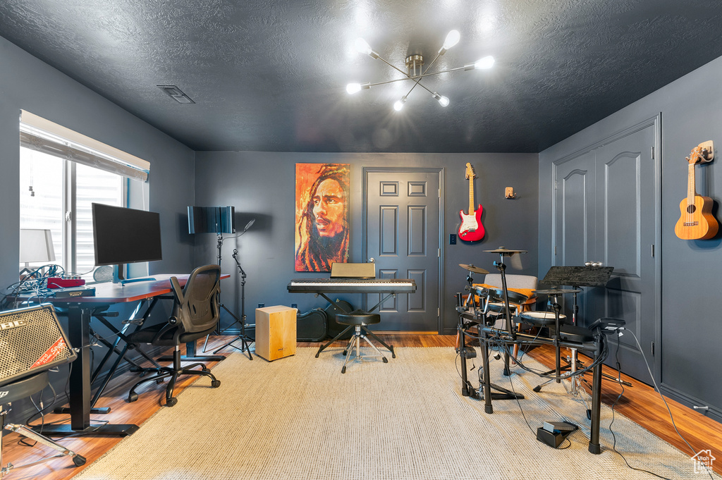 Office area featuring wood finished floors, visible vents, and a textured ceiling