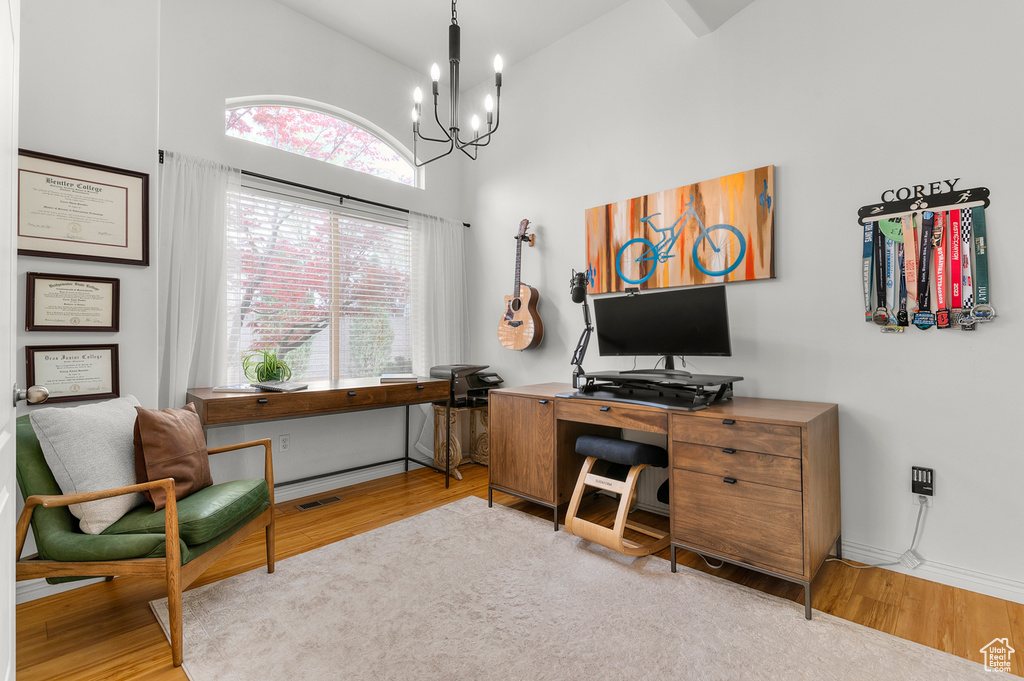 Office with baseboards, wood finished floors, high vaulted ceiling, and a notable chandelier