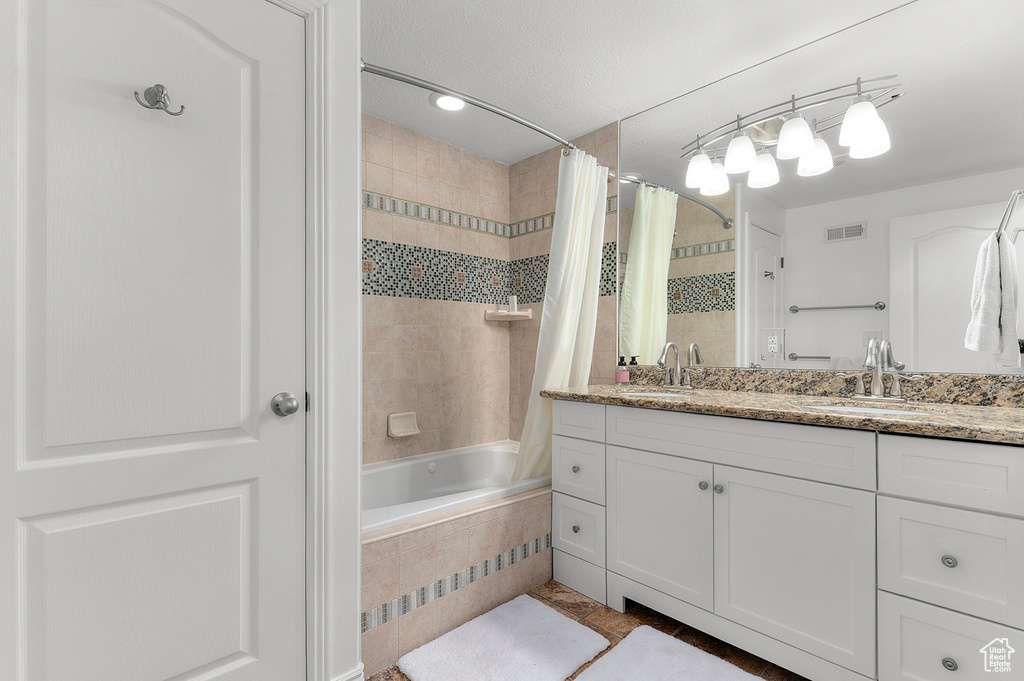 Bathroom with tiled shower / bath combo, visible vents, tile patterned floors, and vanity