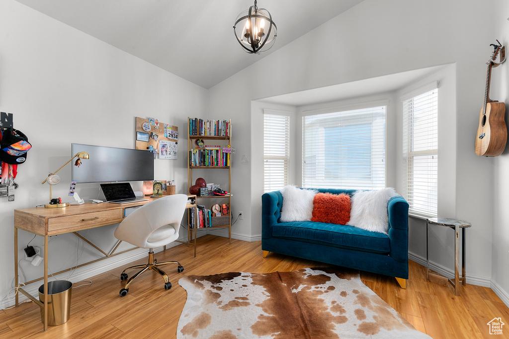 Office featuring lofted ceiling, baseboards, wood finished floors, and an inviting chandelier