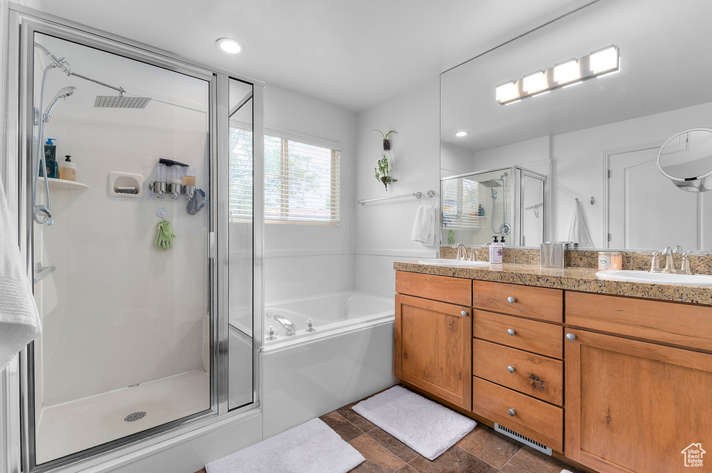 Bathroom with double vanity, a shower stall, a garden tub, and a sink
