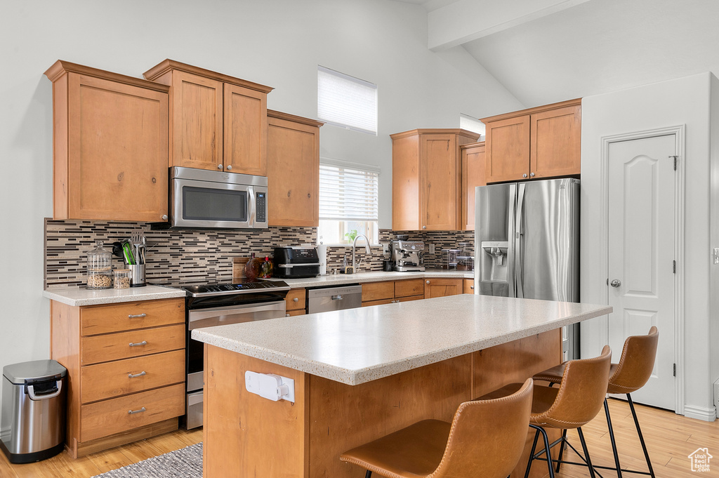 Kitchen featuring stainless steel appliances, light countertops, beam ceiling, and backsplash