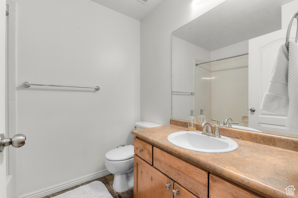 Bathroom with a shower, toilet, vanity, and tile patterned floors