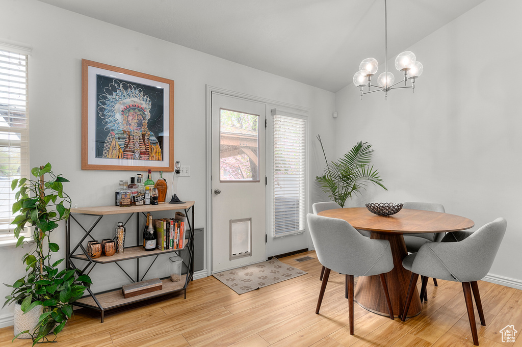 Dining space featuring light wood-style floors, plenty of natural light, lofted ceiling, and an inviting chandelier