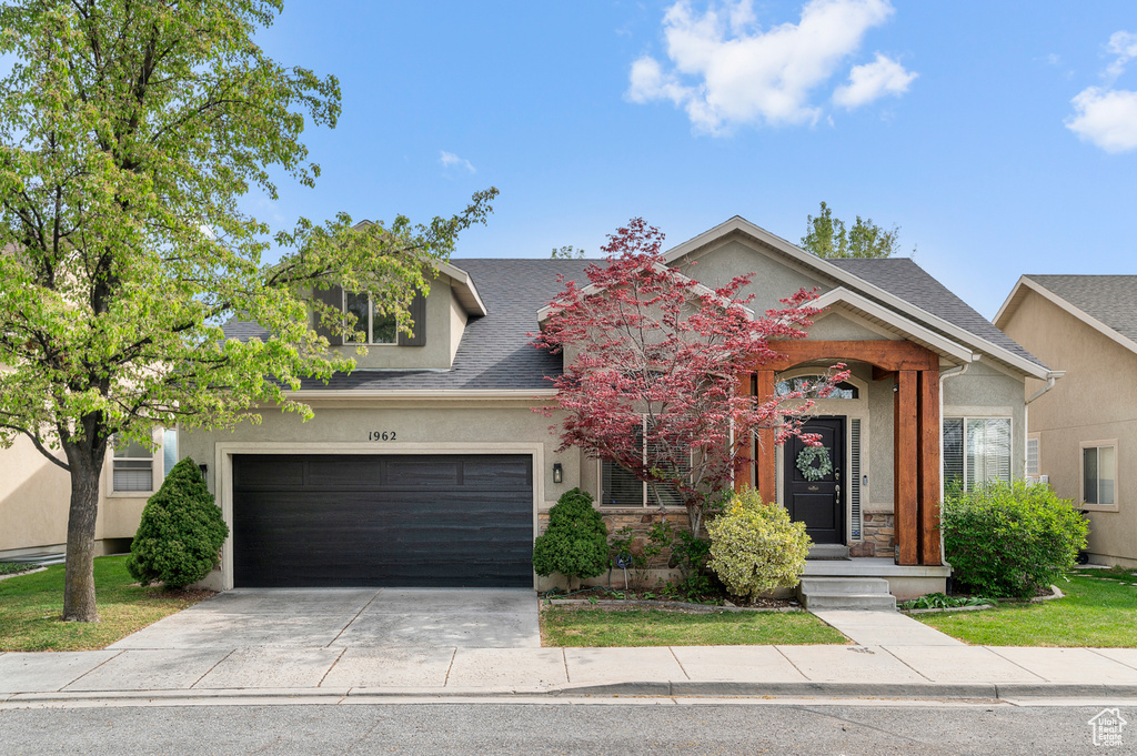 View of front facade featuring a garage, a shingled roof, driveway, and stucco siding