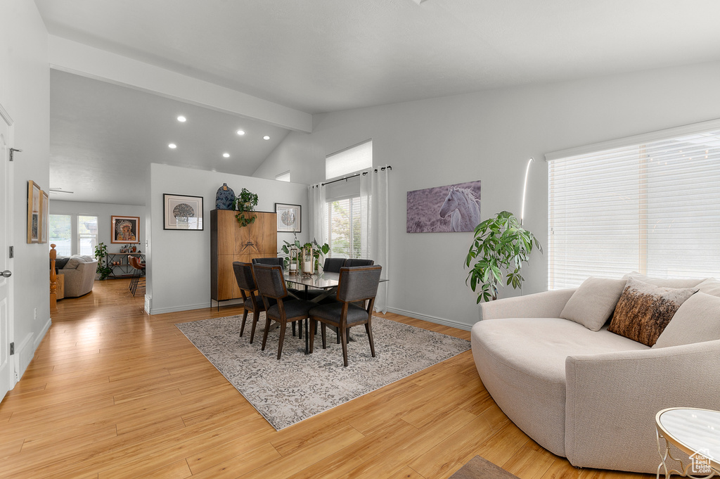 Dining room with lofted ceiling with beams, a wealth of natural light, and light wood-style floors