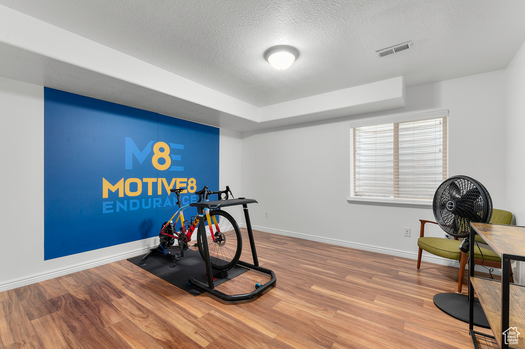 Workout room with baseboards, wood finished floors, visible vents, and a textured ceiling