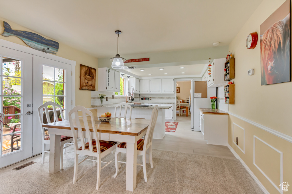 Dining area featuring french doors, visible vents, and a wainscoted wall
