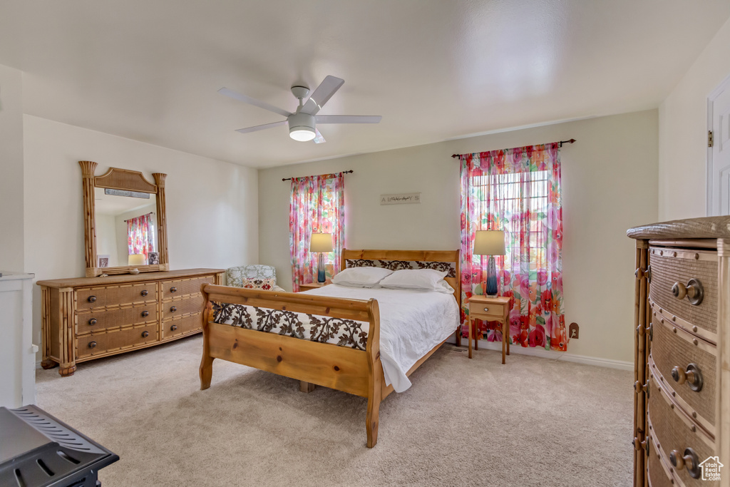 Bedroom featuring baseboards, carpet flooring, a ceiling fan, and multiple windows