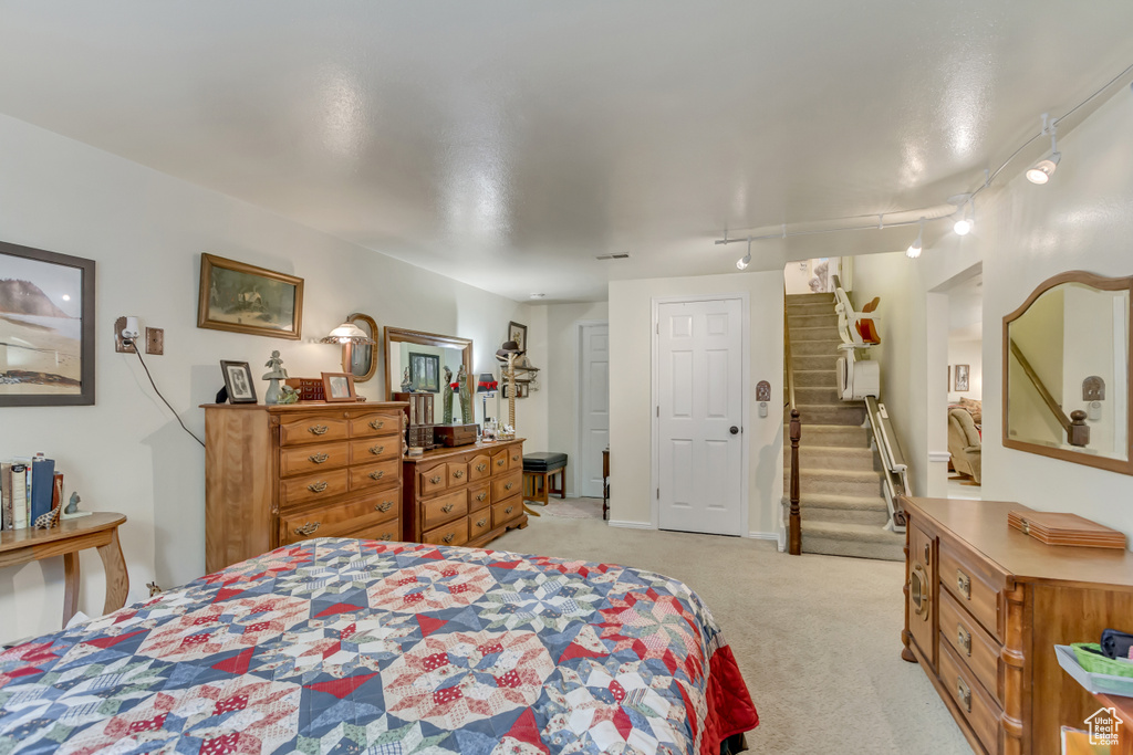 Bedroom with track lighting and light carpet