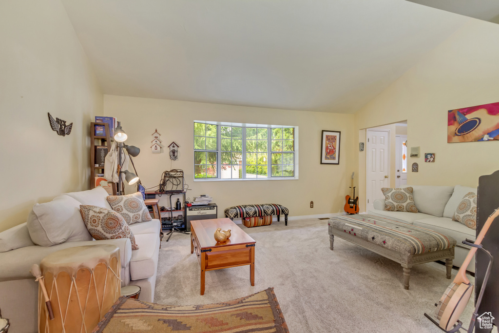 Living area with vaulted ceiling, baseboards, and carpet floors
