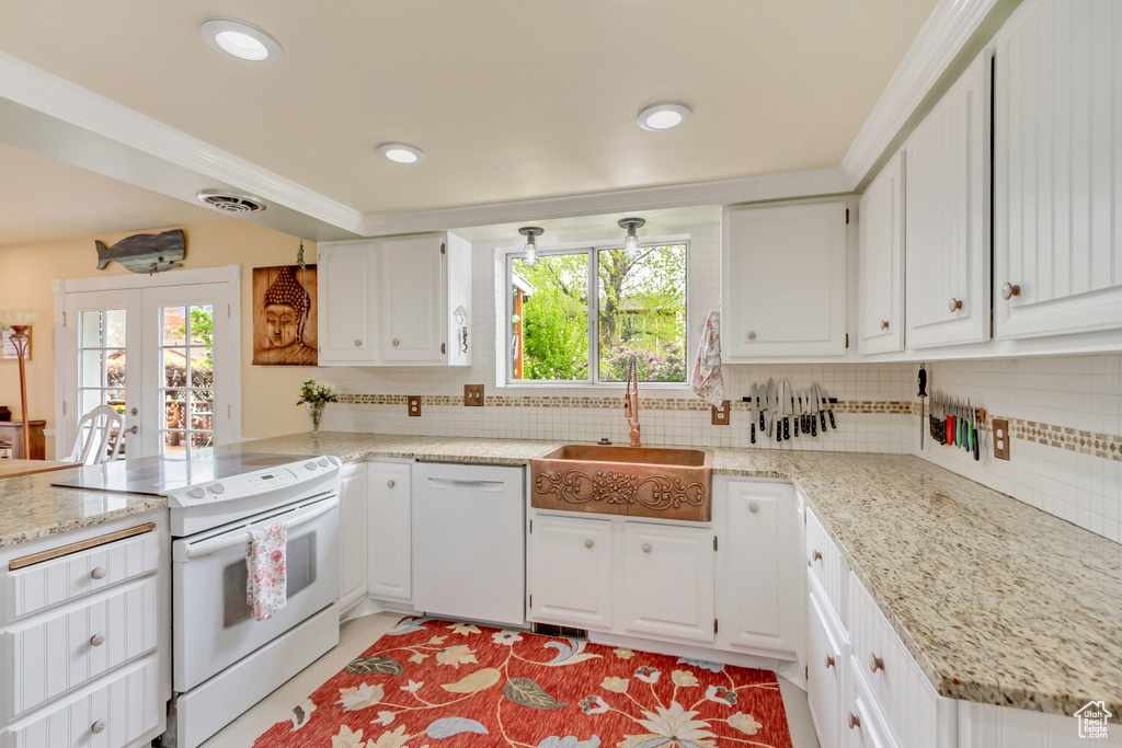 Kitchen featuring a peninsula, a sink, white appliances, and a wealth of natural light