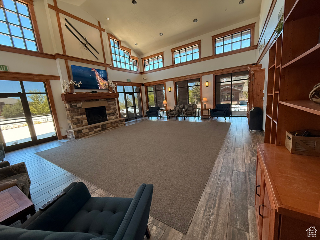 Living area with hardwood / wood-style flooring, high vaulted ceiling, a stone fireplace, and recessed lighting